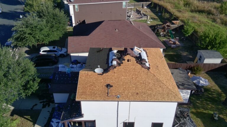 Storm-damaged roof mid tear-off with exposed decking, Austin
